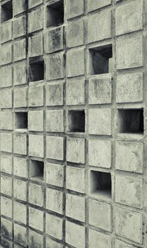 Weathered minimalist concrete breeze block wall texture. Modern industrial geometric hollow concrete roster tile patterns for architectural-themed content backdrop. 