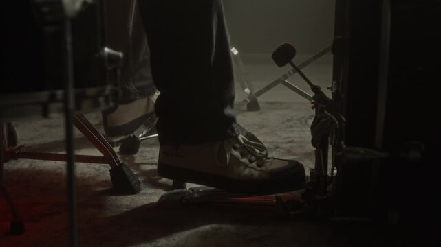 Low section shot of anonymous musician pressing bass drum pedal with foot during studio recording session. Footage for music school promos, concert trailers, or instrument ads