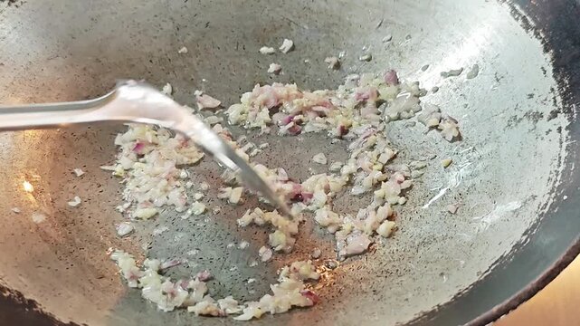 Saut&eacute;ing finely minced garlic and shallots in a traditional wok close up.