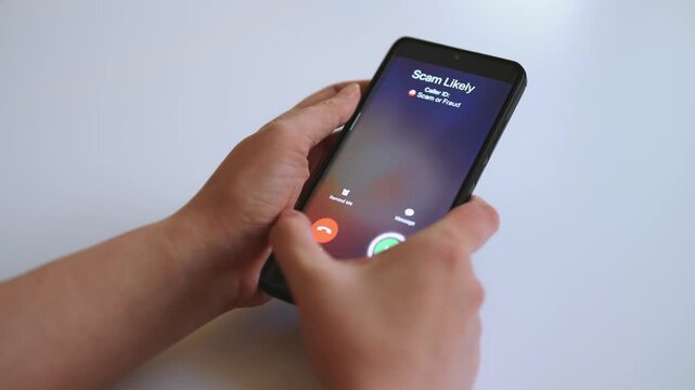 Woman holding smartphone with incoming scam call on screen.