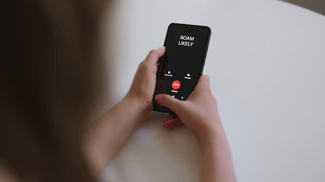 Woman holding smartphone with incoming scam call on screen.