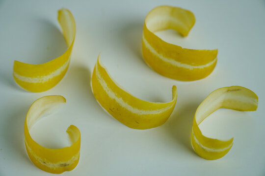 Curled Yellow Peels with White Stripes Artistically Arranged on Light Surface