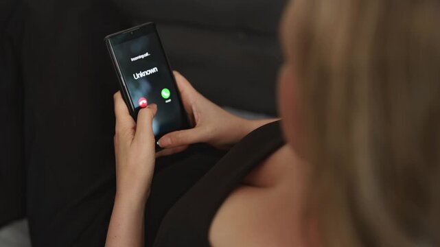Woman holding smartphone with incoming call from unknown suspicious caller.