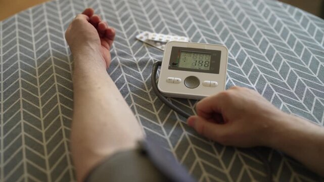 Man measuring blood pressure with digital tonometer at home.
