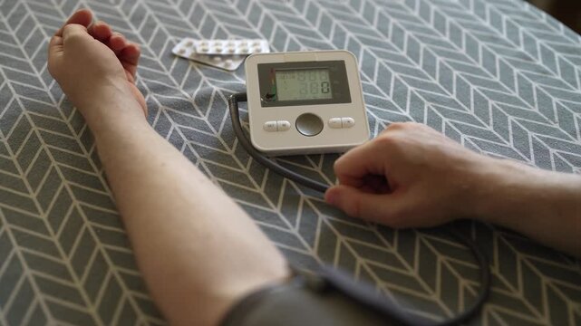 Man measuring blood pressure with digital tonometer at home.