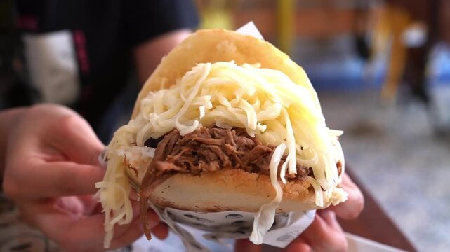 Closeup of Traditional Venezuelan Arepa with Shredded Beef and Shredded Cheese, slow motion 