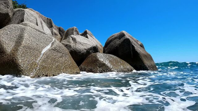 Ocean Waves Splashing Over Large Coastal Granite Rocks on a Sunny Beach