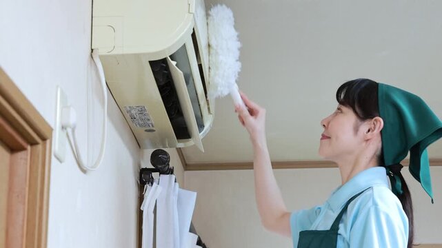 ハンディモップでエアコンを掃除する女性スタッフ