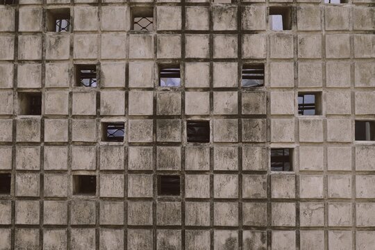Weathered minimalist concrete breeze block wall texture. Modern industrial geometric hollow rustic concrete roster tile patterns for architectural-themed content 