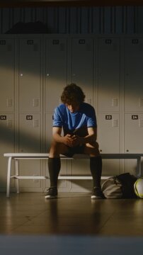 While Rest of Youth Team Changing and Talking in Background, Coach Offers Words of Encouragement to Upset Boy. Importance of Mental Health Support, Mentorship, Empathy in Youth Sports. Vertical Shot.