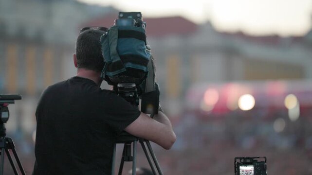Camera operator capturing footage of crowd during football championship event in Lisbon, with vibrant atmosphere and excitement visible in the background