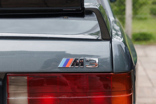 Ljubljana, Slovenia - 2 June 2026: The rear view of a BMW M3 E30, highlighting the rear spoiler and M badging amid a green backdrop.