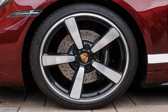 Ljubljana, Slovenia - 2 June 2026: The alloy wheel of a Porsche 911 Targa 4S parked on a stone surface. The car displays its iconic Porsche badge prominently.