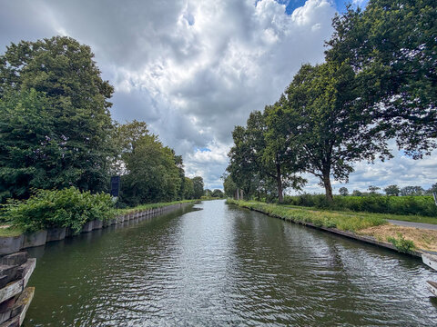 Tranquil Tree-Lined Canal in Rijkevorsel, Belgi&euml; &mdash; Serene Summer Waterway with Dramatic Clouds