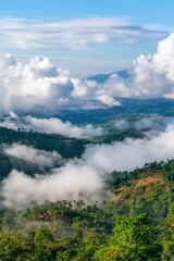 Fototapeta premium Lush green mountains shrouded in mist under a bright blue sky