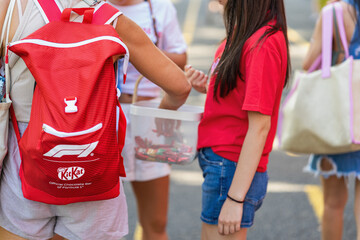 Obraz premium Formula 1 and KitKat Branded Backpack at Burgas Public Event. Participant person wears red backpack displaying Formula 1 and Nestle KitKat branding, Burgas, Bulgaria
