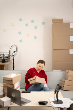 Working at home. SME business woman use laptop checking customer order online shipping boxes working at home office. Starting Small business entrepreneur. SME.