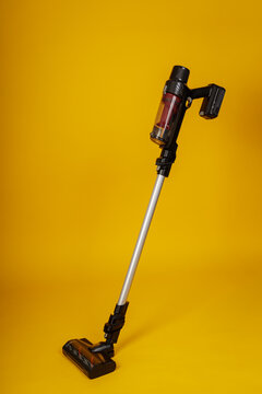 Cordless Stick Vacuum Cleaner with Detachable Handheld Unit on Yellow Background, Modern Home Appliance Product