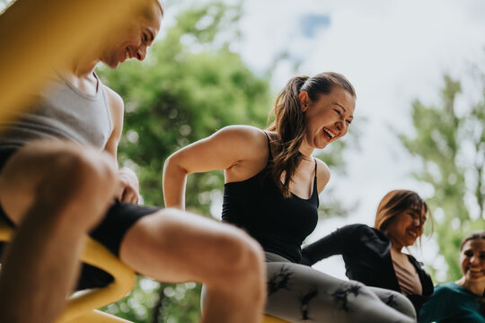 A group of women performing outdoor exercises while laughing and supporting each other. Friends enjoy a casual park workout and social fitness session together.