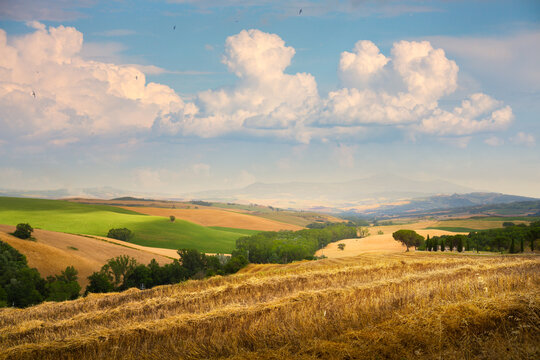 Summer Patchwork countryside fields in Tuscany, harvested hay and rolling hills under summer sky, Italy