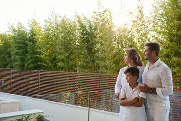 Fototapeta premium Family On Balcony At Home Enjoying Sea View From Rooftop Terrace At Sunset