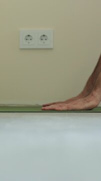 Vertical video Laying underlay for the laminate flooring. Preparatory work before laying a laminate board. Laying a polypropylene substrate under the laminate. Renovation of a new house.