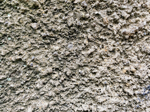 A close up view of a coarse and gritty concrete wall surface with a natural gray stone texture.