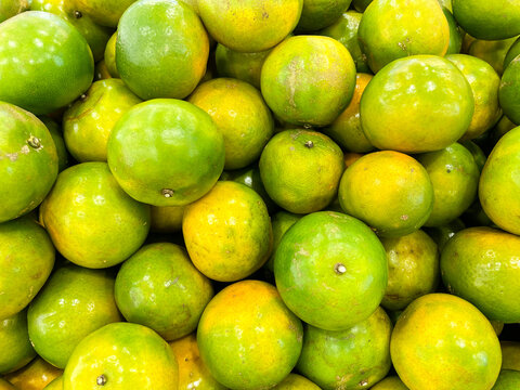 A close up top view of a pile of fresh and ripe green oranges with citrus texture.