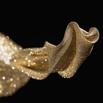 Golden glitter waving on black background. Studio shot using high speed technique, selective focus.
