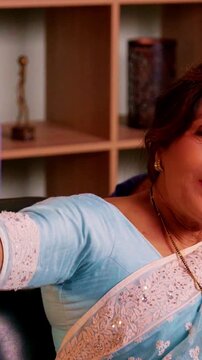 Asian Indian cute senior couple relaxing in their modern home, with the wife taking a cheerful selfie while her husband happily poses and capture a precious moment
