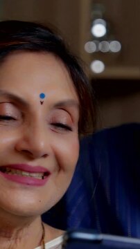 Happy elderly Indian couple sitting at home on a sofa  enjoying a video call  having warm conversations