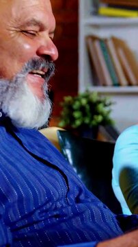 Retired Indian couple sitting together in their modern home, reading a newspaper, discussing news with curiosity and surprise