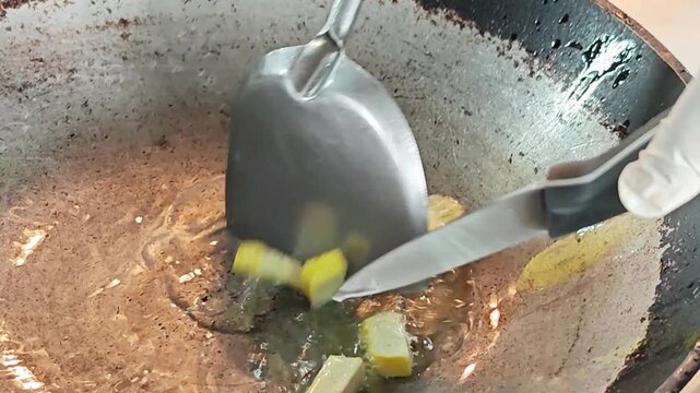 Frying diced yellow tofu in a traditional metal wok close up.