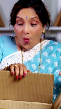 Charming Asian Indian elderly couple feeling happy and  excited while opening a parcel from their online shopping
