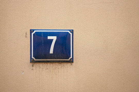 Blaues Schild mit der Hausnummer 7, Sieben an einer Fassade in der Altstadt von T&uuml;bingen in Deutschland