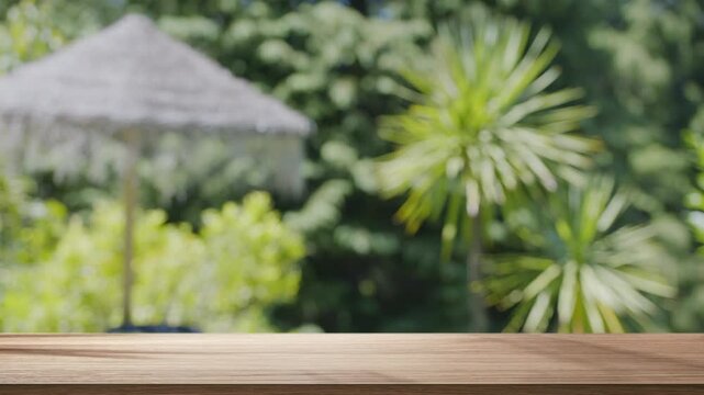 Empty wooden tabletop with a softly blurred, looping background of tropical palm leaves and trees moving in a gentle breeze.
