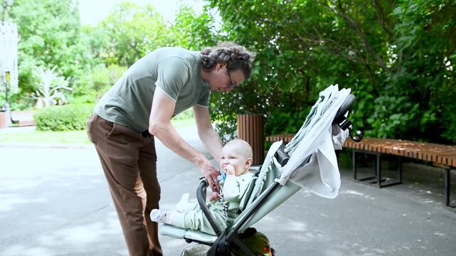 A father carefully secures his little son in the stroller, making sure every strap is snug and comfortable.