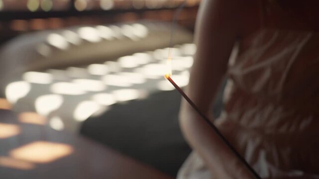 Woman lighting incense stick for aromatherapy