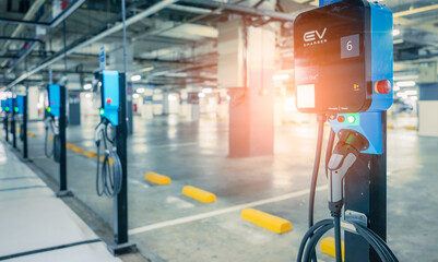 Fototapeta premium Electric car charging station for charge EV battery. Plug for vehicle with electric engine. EV charger. Clean energy. Charging point at car parking lot. Green power. Future transport technology.