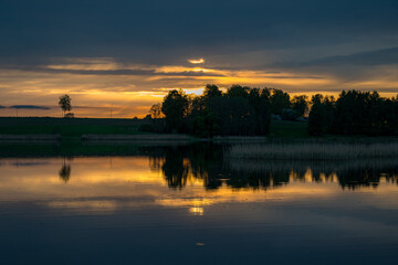 Naklejka premium beautiful sunset, sunrise landscape by the lake, reflections on the surface of the calm lake water, bright colors,