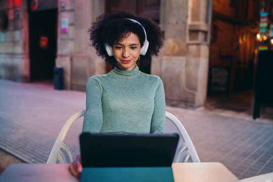 young Hispanic woman taking smiling selfie portrait via smartphone camera while sitting inside cozy city coffee shop terrace, cheerful Gen Z user sharing live travel blog updates online