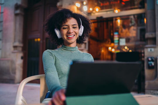 young Hispanic woman enjoying online banking mobile application interface on smartphone touchscreen, happy Gen Z user checking secure electronic money transfer notification on cafe terrace table