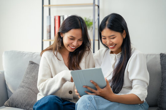 Two young Asian women are using digital tablet to browse social media, shopping online, study, work