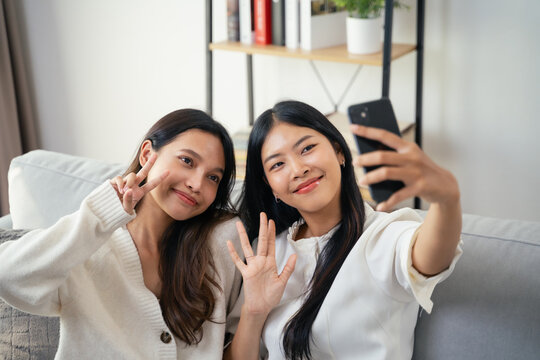 Two young Asian women are take selfies with smartphone and waving to the camera