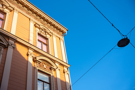 Zagreb, Croatia - August 22, 2025: Ornate classical building facade illuminated by golden sunlight against a vivid blue sky. The detailed architectural elements and sharp shadow lines emphasize the el
