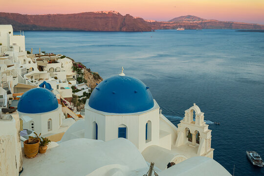 Sunset over Oia&rsquo;s iconic blue-domed churches overlooking the Aegean Sea, capturing the serene beauty and timeless architecture of Santorini&rsquo;s caldera &mdash; a breathtaking Mediterranean travel destination.