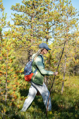 Naklejka premium Confident woman backpacker strolling through forest, physical activity outdoors and healthy living, female solo hiking in woodlands, walking making way on trekking path in thickets, getaway in nature.