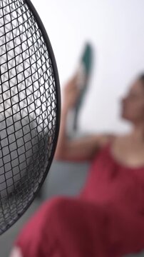 out of focus unrecognizable woman in bed during a hot summer heat wave with fan, cooling off fighting heat at home during a heatwave and high temperature, vertical