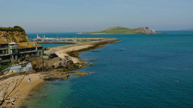 Scenic panorama overlooking Balscadden Bay, Howth Harbour, Ireland&rsquo;s Eye island, turquoise water, rocky shoreline, marina, lighthouse, peaceful summer atmosphere, Dublin spectacular eastern coastline.