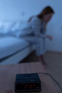 Clock shows 2 am while woman sits on bed